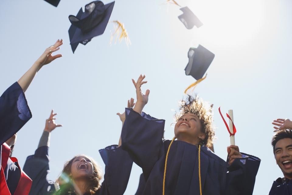 college graduates throwing mortarboards into the air