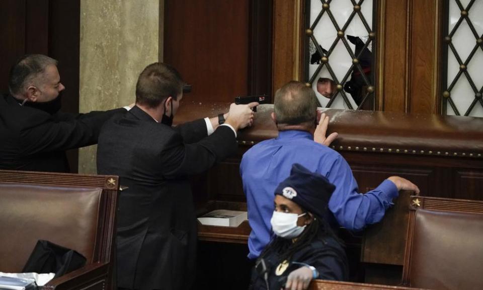 Police with guns drawn watch as protesters try to break into the House Chamber at the US Capitol.