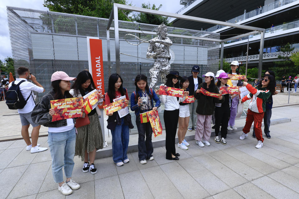 Fans of Spain's Rafael Nadal pose for pictures with his statue ahead of his first round match of the French Open tennis tournament against Germany's Alexander Zverev at the Roland Garros stadium in Paris, Monday, May 27, 2024. (AP Photo/Aurelien Morissard)