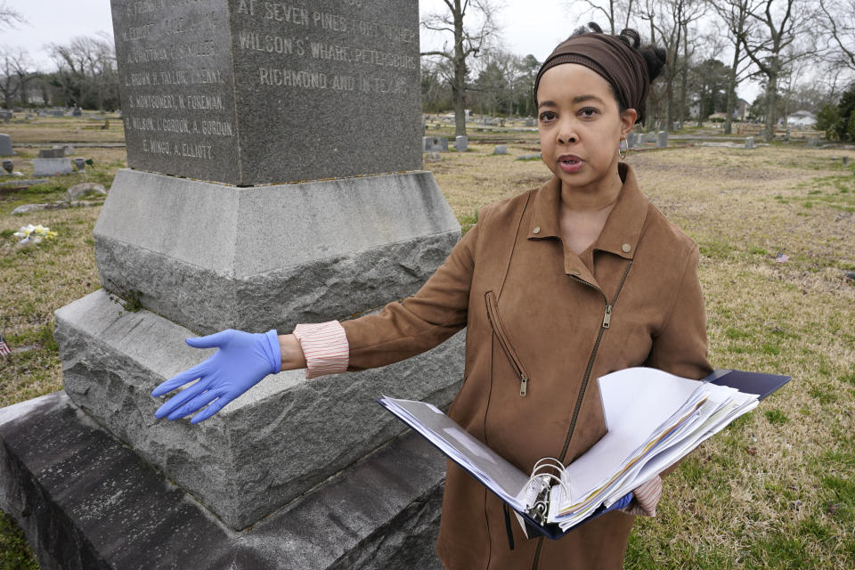 Nadia Orton, a genealogist and family historian in Virginia, holds a binder of research next to a monument to black Civil War Union soldiers at the Lincoln Memorial Cemetery in Portsmouth, Va., Tuesday, March 23, 2021. Orton has worked tracing her own family and others to historically Black cemeteries. (AP Photo/Steve Helber)