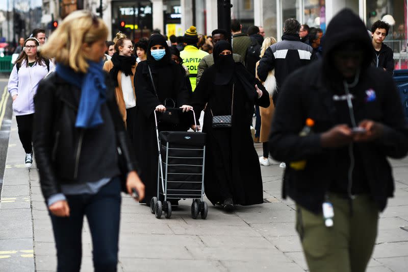 Muslim women wear faces masks as they walk in London