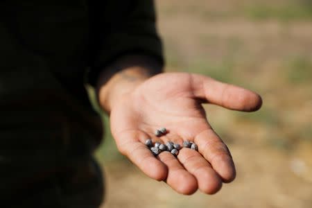 An Israeli soldier holds metal balls in a site where a rocket fell near the Israeli Kibbutz of Nachal Oz, on the Israeli side of the Israel - Gaza border July 14, 2018 REUTERS/Amir Cohen