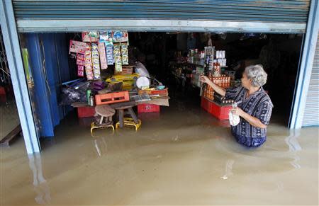 A resident walks outside a flooded shop at Srimahaphot district in Prachin Buri province, east of Bangkok September 24, 2013. REUTERS/Chaiwat Subprasom