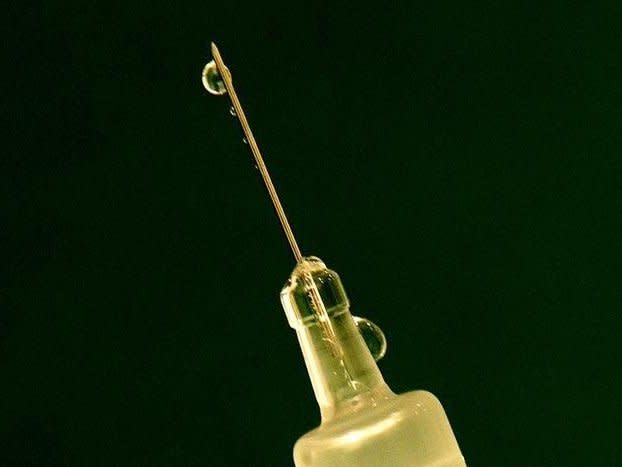 Flu vaccine drips out of a syringe as a nurse prepares for a patient at a clinic in central London November 22, 2005. HEALTH REUTERS/Dylan Martinez