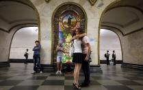 A couple hugs in front of a stained glass panel in Novoslobodskaya metro station, which was built in 1952, in Moscow August 17, 2013. To step onto the Moscow metro is to step back in time and immerse yourself in a museum rich in architecture and history. Opened in 1935, it is an extravagant gallery of Communist design, featuring Soviet artworks, statues, chandeliers, stained glass and ceiling mosaics. Built under Stalin, the metro now transports 7 to 9 million people a day and costs 30 Rubles, around $1, for a single ride. Picture taken August 17, 2013. REUTERS/Lucy Nicholson (RUSSIA - Tags: TRANSPORT SOCIETY) ATTENTION EDITORS: PICTURE 06 OF 24 FOR PACKAGE 'RIDING THE MOSCOW METRO' SEARCH 'MOSCOW CHANDELIERS' FOR ALL IMAGES