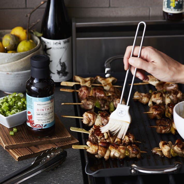 basting skewers over grill with silicone brush