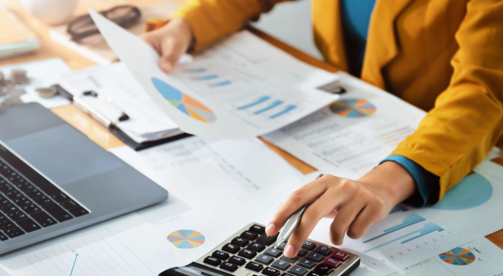 Accountant uses a calculator while looking at graphs. Finance. COWN stock.