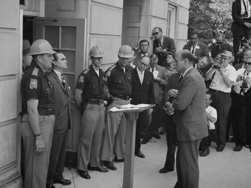 George Wallace attempting to block integration at the University of Alabama, standing defiantly at a door while being confronted by US Deputy Attorney General Nicholas Katzenbach, 11 June 1963.