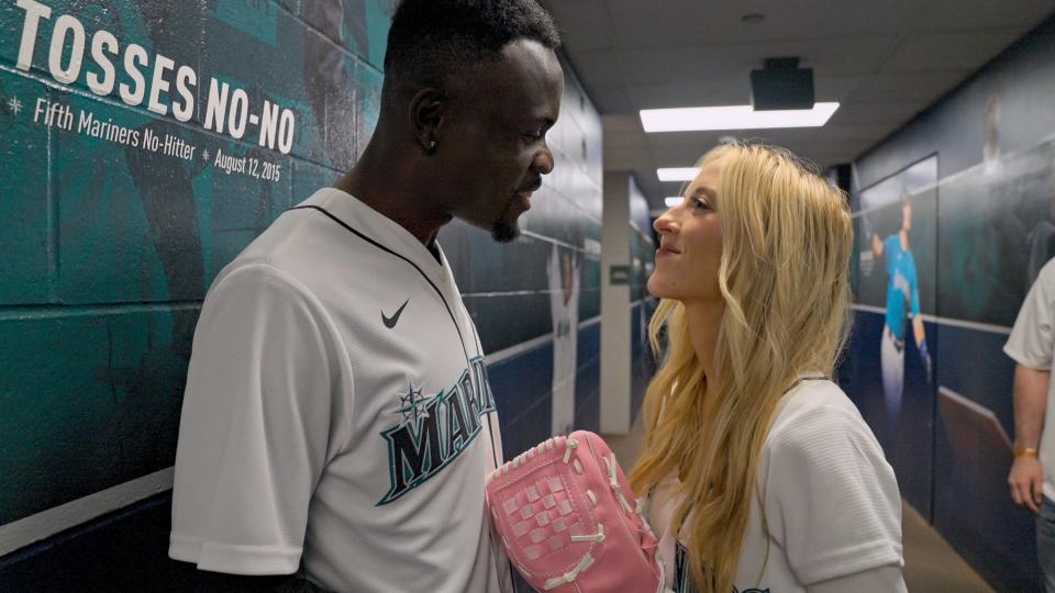 Kwame Appiah and Chelsea Griffin smile at each other wearing Mariners jerseys on 
