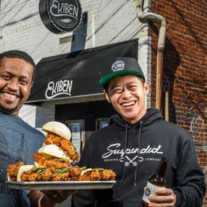 Abebe (left) and Chu holding up food in front of their restaurant