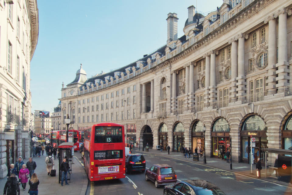 People walking and shopping on the sidewalks of the major shopping street of Regent Street in London.