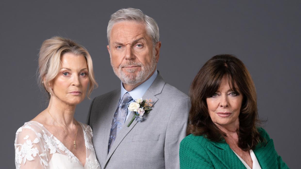  EastEnders' Kathy Beale in a wedding dress, Rocky Cotton in a grey wedding suit and Jo Cotton smirking in a green blazer. 