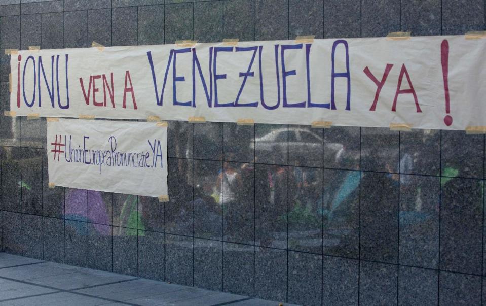 A banners is posted on the wall of the United Nations offices in Caracas, Venezuela, Tuesday, March 25, 2014. The banners reads in Spanish "UN come to Venezuela now" and the one below reads "European Union pronounce yourself". A large group of protesting anti-government students have camped in front of the office of the United Nations asking it to come and observe the situation, as Venezuela’s bloody political standoff heads into its third month. The decision to pitch tents on the concrete sidewalk along one of Caracas’ busiest, smog-filled streets comes as foreign ministers from several South American nations arrive Tuesday to lend support to President Nicolas Maduro’s efforts at reconciliation with his opponents. (AP Photo/Fernando Llano)