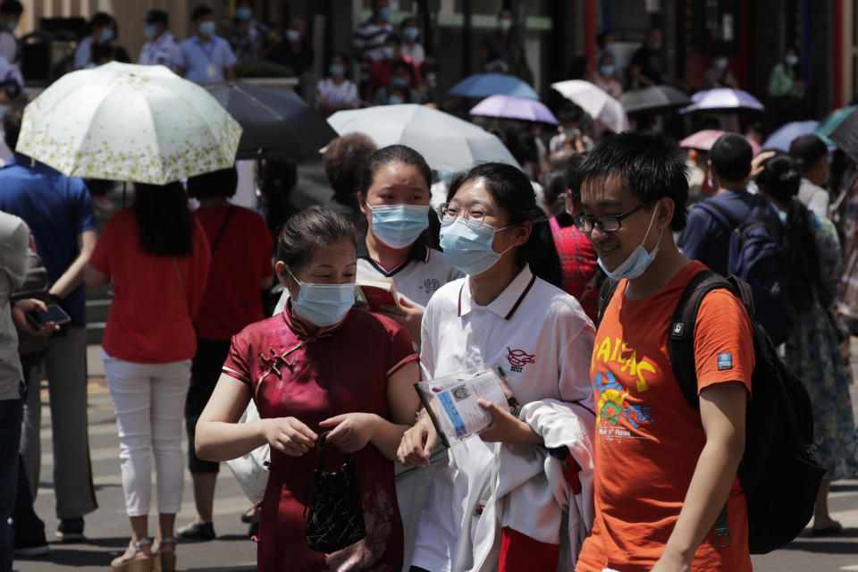 Students wearing face masks to protect against the new coronavirus is accompanied by their relatives leave the school after finishing the first day of China's national college entrance examinations, known as the gaokao, in Beijing, Tuesday, July 7, 2020. China's college entrance exams began in Beijing on Tuesday after being delayed by a month due to the coronavirus outbreak. (AP Photo/Andy Wong)