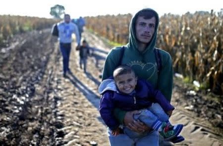 A man carries a child as migrants walk to cross the border into Croatia, near Sid, Serbia, October 2, 2015. REUTERS/Dado Ruvic