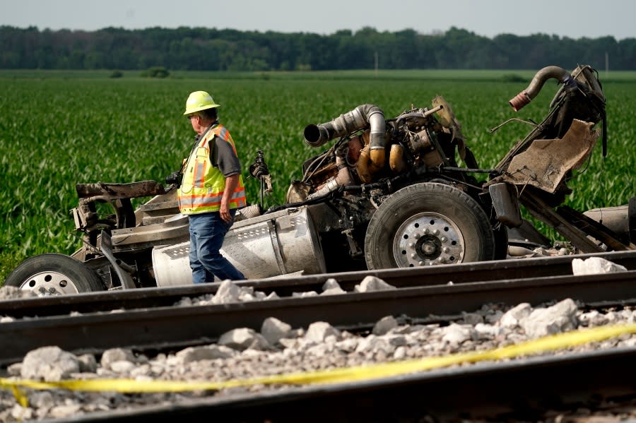 A worker looks over a dump truck that collided with an Amtrak train, causing it to derail Monday, June 27, 2022, near Mendon, Mo. (AP Photo/Charlie Riedel)