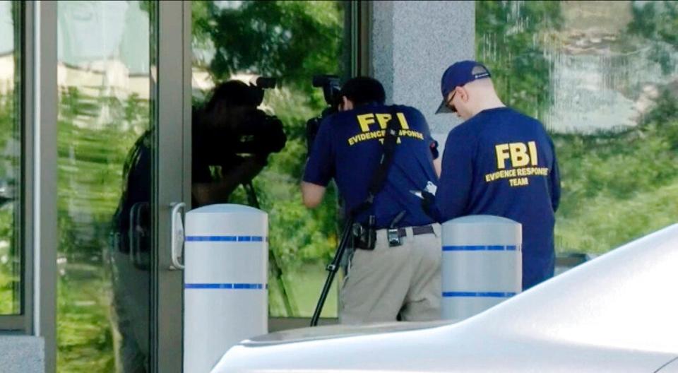 In this still image taken from WKEF/WRGT video, members of the FBI Evidence Response Team work outside the FBI building in Kenwood, Ohio, Thursday, Aug. 11, 2022. An armed man decked out in body armor tried to breach a security screening area at an FBI field office in Ohio, then fled and was injured in an exchange of gunfire in a standoff with law enforcement, authorities said.