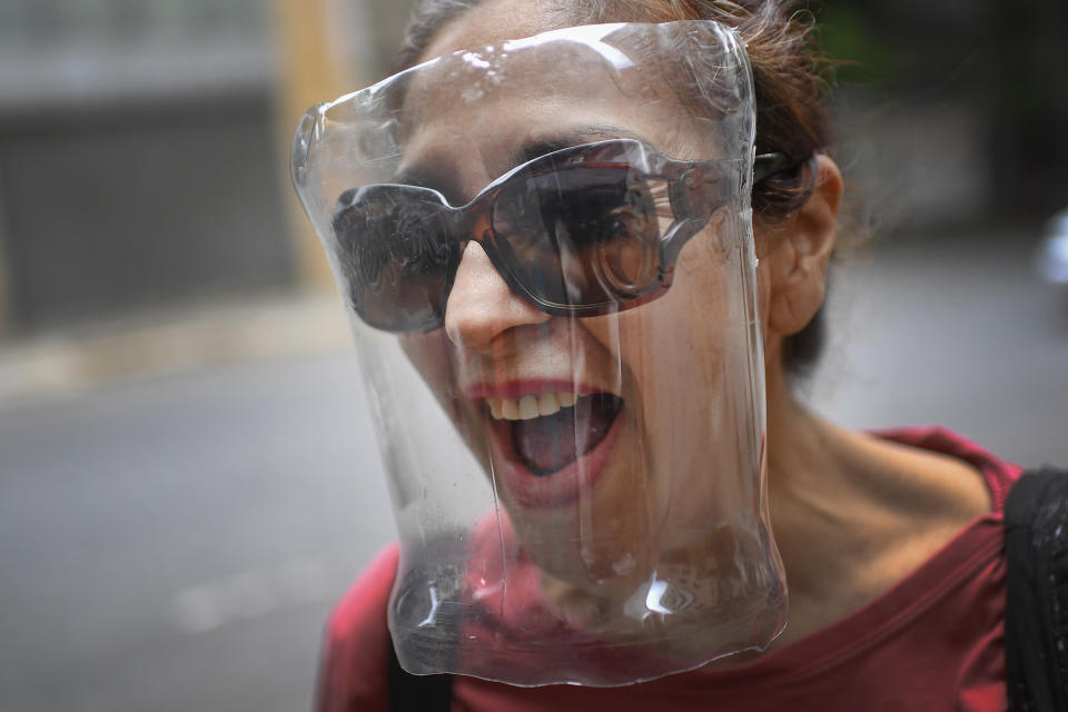 A woman wears a face shield made from a plastic bottle container, amid the spread of the new coronavirus in Caracas, Venezuela, Saturday, April 18, 2020. (AP Photo/Matias Delacroix)