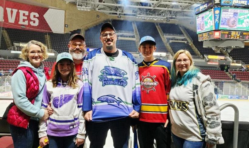 Illinois Flying Carp jersey designer Tyler Earles (middle) with (left-to-right) sister-in-law Heather Thompson, niece Isla Thompson, brother-in-law Michael Thompson, nephew North, and wife Robyn Earles, at the Peoria Rivermen game on March 10, 2023, in which the team re-branded for one night as the Illinois Flying Carp in an SPHL game at Carver Arena. The Thompson family are Rivermen season ticket holders and Morton natives.