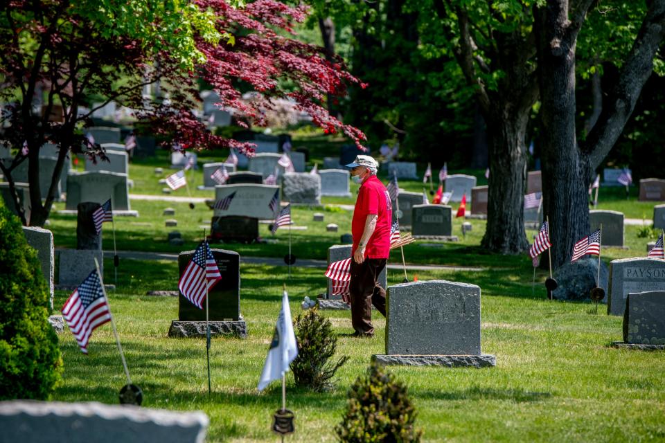 U.S. Air Force veteran Dick Santoro, who served during the Vietnam War, walks through First Parish Cemetery in York Village, Maine, on Friday, May 21, 2021, placing American flags on the graves of veterans.