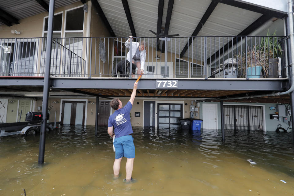 Rudy Horvath hands a piece of wood up to his wife Dawn Horvath, as their home, a boathouse in the West End section of New Orleans, takes on water a from storm surge in Lake Pontchartrain, in advance of Tropical Storm Cristobal, Sunday, June 7, 2020. (AP Photo/Gerald Herbert)