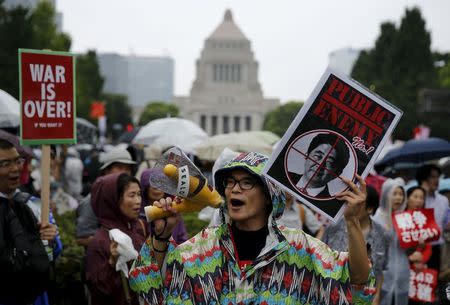 People hold placards and shout slogans as they protest against Japan's Prime Minister Shinzo Abe's security bill outside parliament in Tokyo August 30, 2015. REUTERS/Thomas Peter