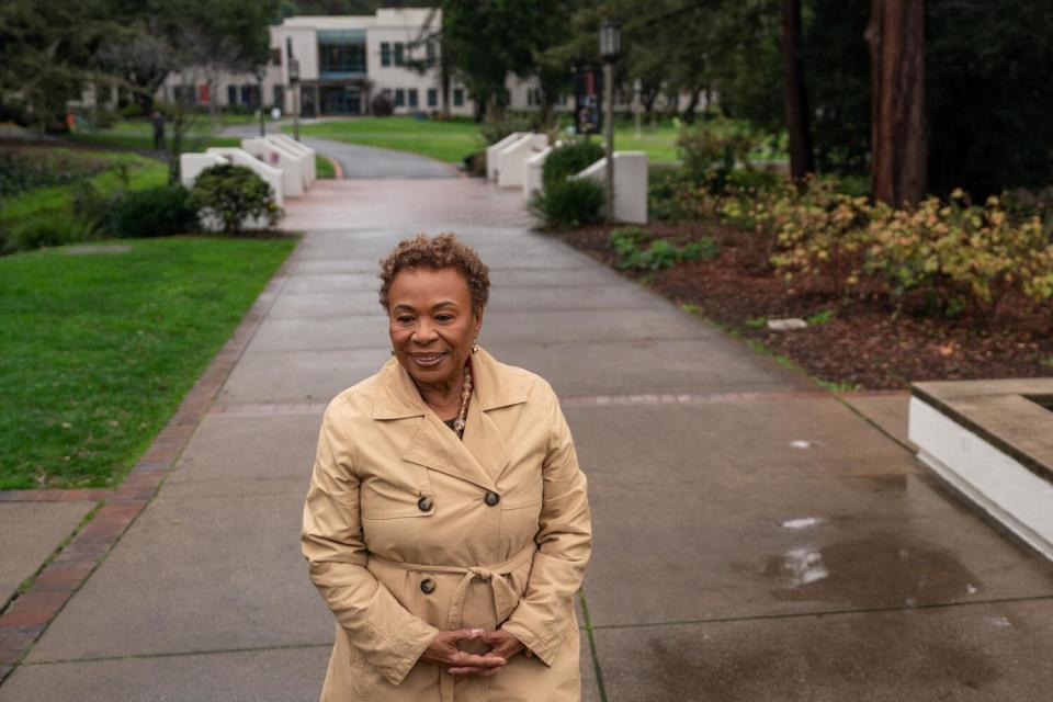 Barbara Lee stands on a college campus outdoors in a coat.