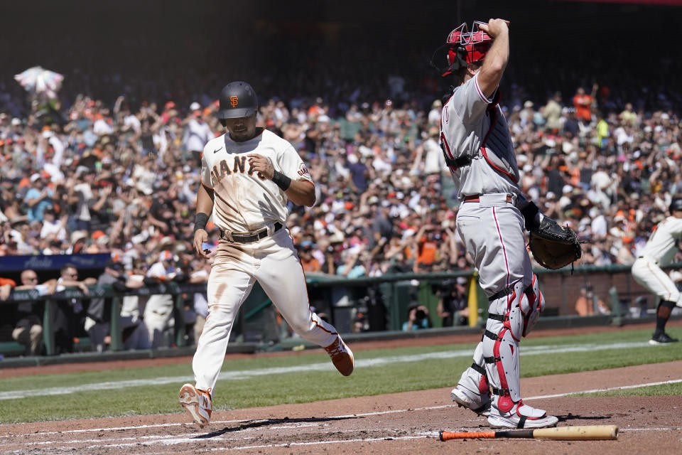 San Francisco Giants' LaMonte Wade Jr., left, scores past Philadelphia Phillies catcher J.T. Realmuto during the third inning of a baseball game in San Francisco, Saturday, Sept. 3, 2022. (AP Photo/Jeff Chiu)