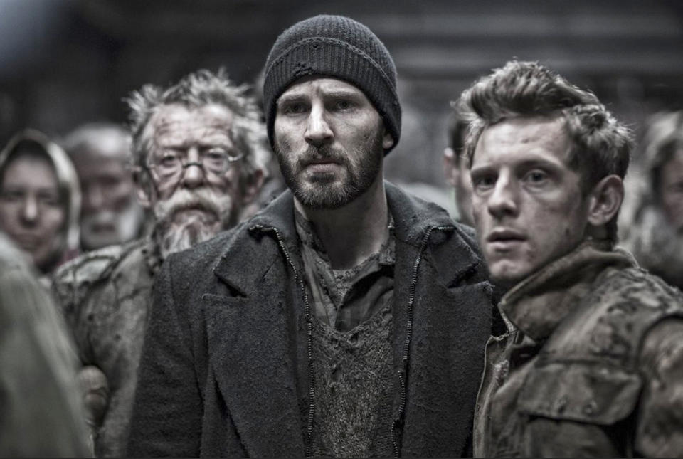 John Hurt, Jamie Bell and Chris Evans examine an concerning situation unfolding in their train car in “Snowpiercer.”