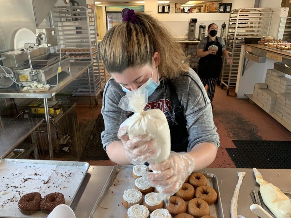 An employee applies icing to a batch of freshly made donuts at the Ormond Beach Donnie's Donuts on Wednesday, Feb. 24, 2021.