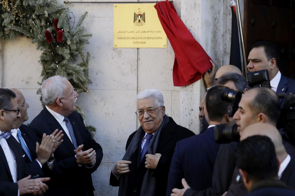 Palestinian President Mahmoud Abbas, center, stands in front of a newly unveiled plaque on the occasion of the inauguration ceremony of the Palestinian embassy to the Holy See at the Vatican, Saturday, Jan. 14, 2017. (AP Photo/Andrew Medichini)