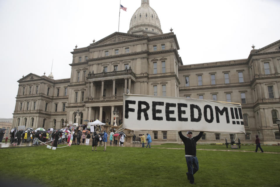 Un hombre muestra un cartel que dice "Libertad" durante una manifestación para protestar los confinamientos por la pandemia del coronavirus frente al capitolio de Michigan en Lansing el 14 de mayo del 2020. (AP Photo/Paul Sancya, File)