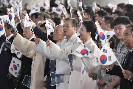 South Korean President Moon Jae-in and his wife Kim Jung-sook wave the national flags during a ceremony to mark the 74th anniversary of Korea's liberation from Japan's 1910-45 rule, at the Independence Hall of Korea in Cheonan