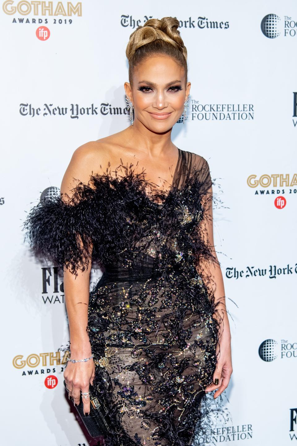 Jennifer Lopez looks stunning in a black dress with gold design and furry edges