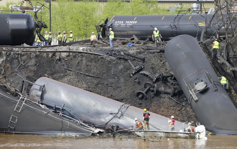 Survey crews in boats look over tanker cars as workers remove damaged tanker cars along the tracks where several CSX tanker cars carrying crude oil derailed and caught fire along the James River near downtown Lynchburg, Va., Thursday, May 1, 2014. Virginia state officials were still trying Thursday to determine the environmental impact of the train derailment. (AP Photo/Steve Helber)