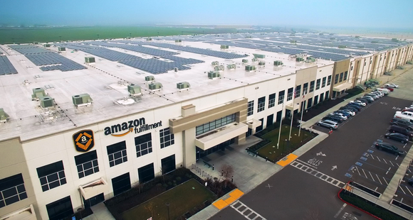 An overhead view of an Amazon Fulfillment Center with a solar panel array on the rooftop.
