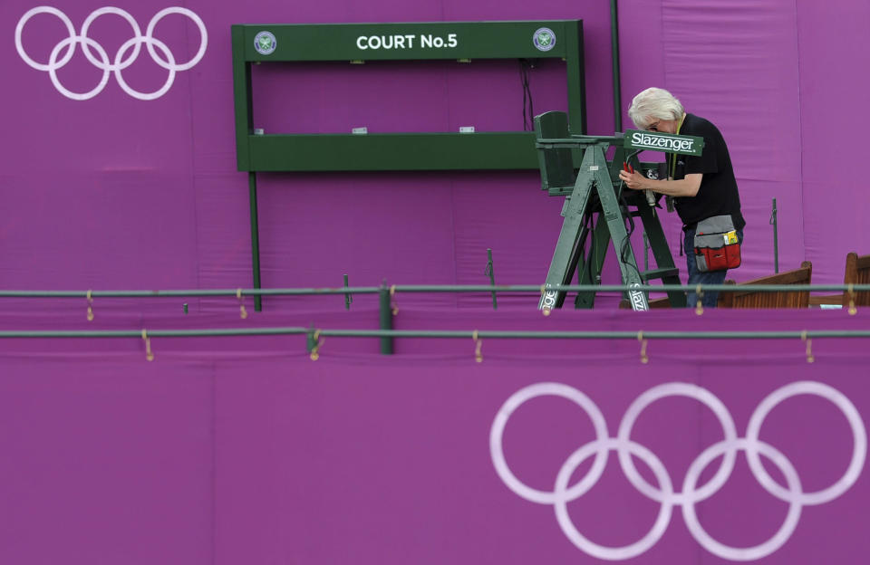 A workman helps erect Olympic hoarding on Court Five at the All England Lawn Tennis Club (AELTC) as preparations are made for the London 2012 Olympic Games, in London July 9, 2012. REUTERS/Ki Price (BRITAIN - Tags: SPORT OLYMPICS TENNIS)