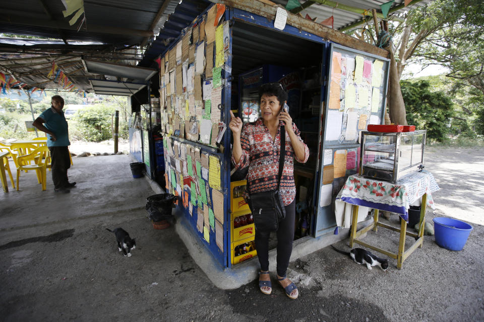 In this Sept. 13, 2018 photo, Martha Elena Alarcon speaks on her cell phone in front of messages written by Venezuelan migrants in gratitude to her, which cover her little store on the side of the road in Los Patios, Colombia. When Venezuelans began arriving at her doorstep about a year ago, she'd give them water and bread, and as the numbers skyrocketed, she asked them to leave a written message. (AP Photo/Fernando Vergara)