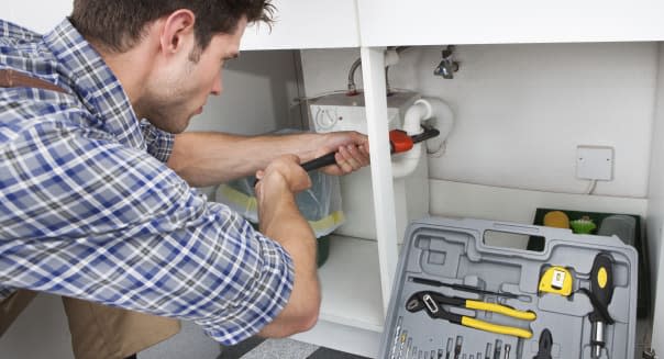 Plumber Fixing Sink In Kitchen