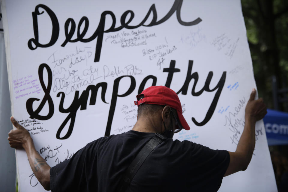 A mourner shows a card as he waits for the casket of Rep. John Lewis to arrive at the state capital as Lewis will lie in repose, Wednesday, July 29, 2020, in Atlanta. Lewis, who carried the struggle against racial discrimination from Southern battlegrounds of the 1960s to the halls of Congress, died Friday, July 17, 2020. (AP Photo/Brynn Anderson)