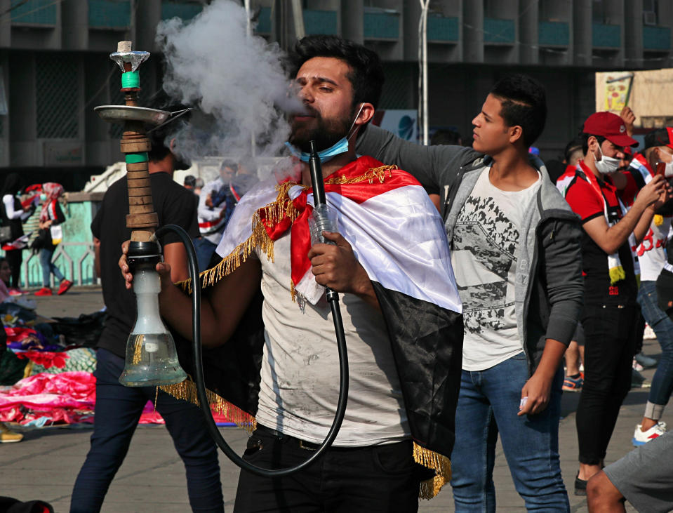 An anti-government protester smokes a water pipe during ongoing demonstrations at Tahrir Square in Baghdad, Iraq, Thursday, Oct. 31, 2019. (AP Photo/Hadi Mizban)