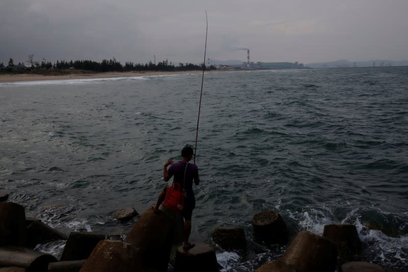 A man stands with a fishing rod by the beach near Formosa steel mill in Ha Tinh province