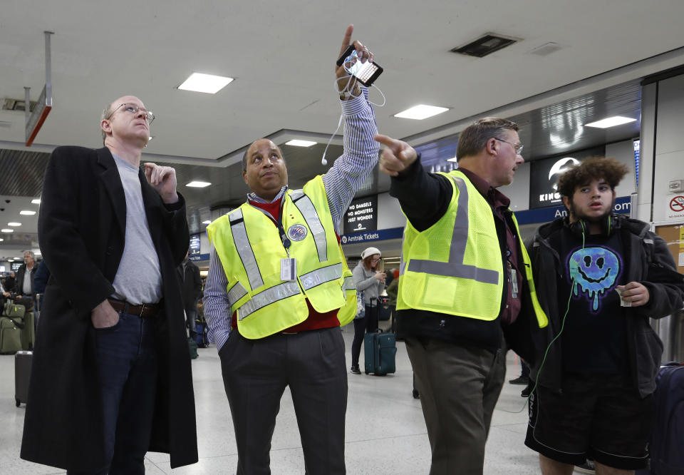 Anthony Navarro, second from left, an Amtrak Ambassador assisting travelers, helps a passenger find the platform for his train, Wednesday, Nov. 21, 2018, in New York's Penn Station. (AP Photo/Mark Lennihan)