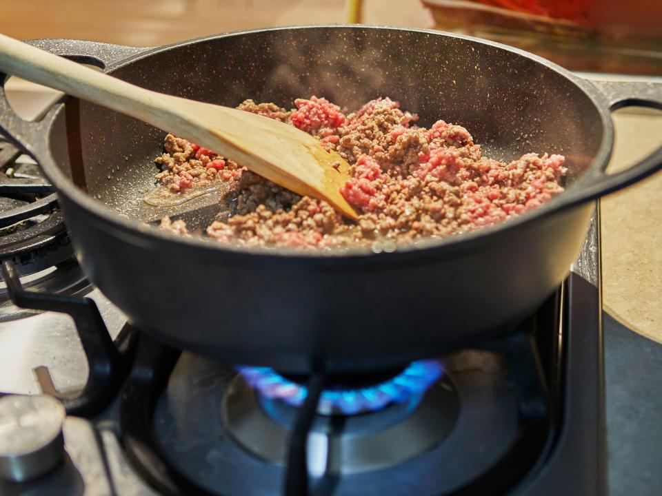 Ground beef cooking in black pan on stove top