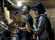 In this July 20, 2018 photo, members of the rock band Arikayn, Afghan musicians Hakim Ebrahimi, center, and Soraya Hosseini, play at a furniture workshop in Eslamshahr, on the outskirts of Iran’s capital, Tehran. The band, made up of Afghan migrants, plays Metallica-inspired ballads about the struggles of millions of Afghans who have fled to Iran to escape decades of war and unrest. In Iran they face discrimination, and have had to contend with hard-liners opposed to Western culture. (AP Photo/Ebrahim Noroozi)