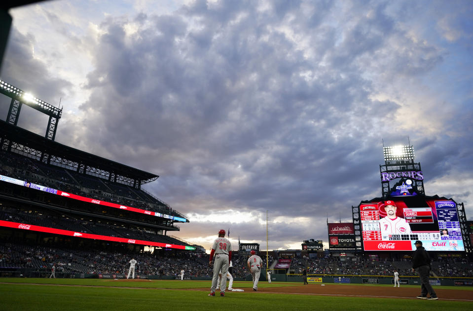 Clouds hang over Coors Field as Cincinnati Reds' Mike Moustakas leads off first base during the fourth inning of the team's baseball game against the Colorado Rockies on Thursday, May 13, 2021, in Denver. (AP Photo/David Zalubowski)