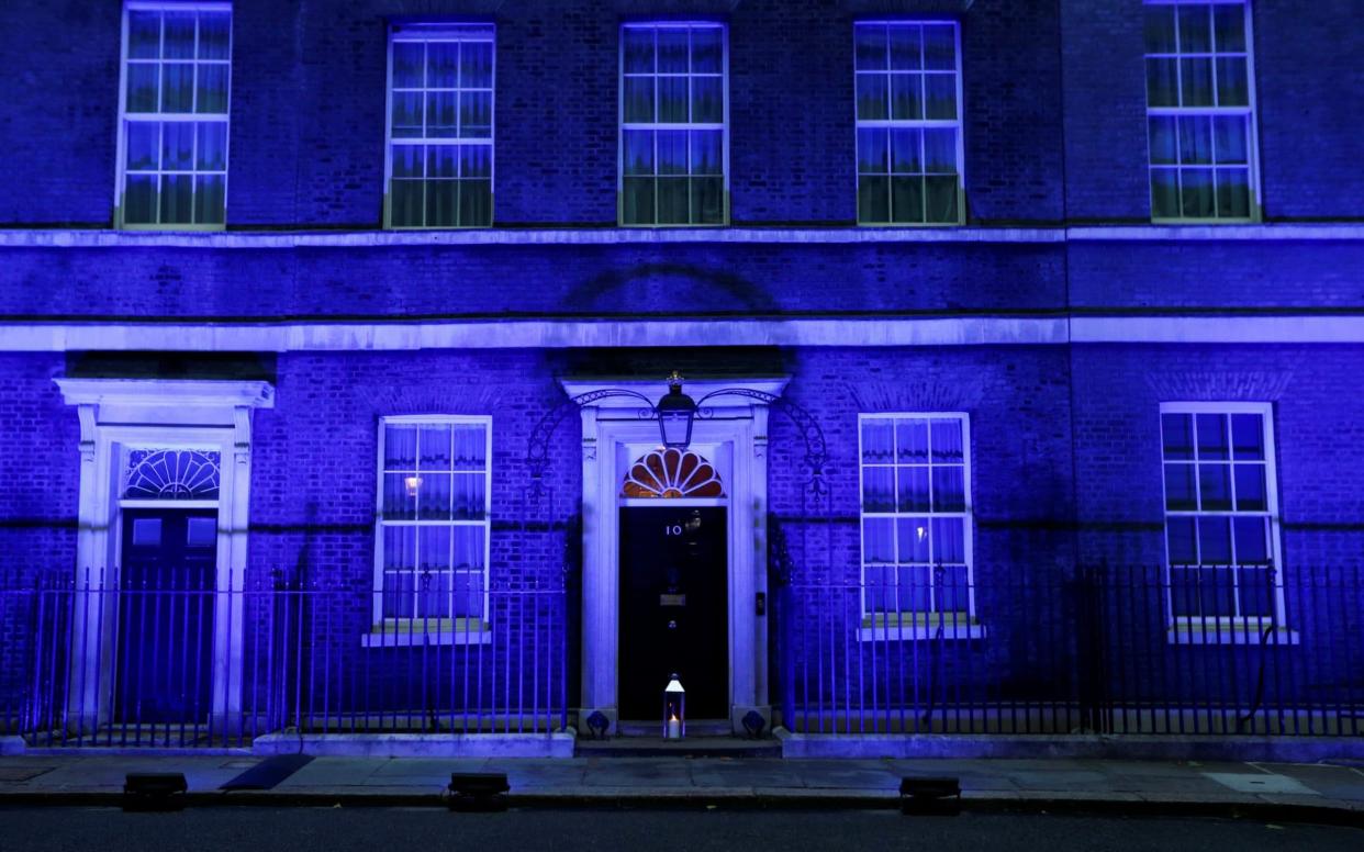A candle lit at the doorstep of 10 Downing Street, illuminated in blue to celebrate the 72nd anniversary of the NHS - REUTERS/Peter Nicholls