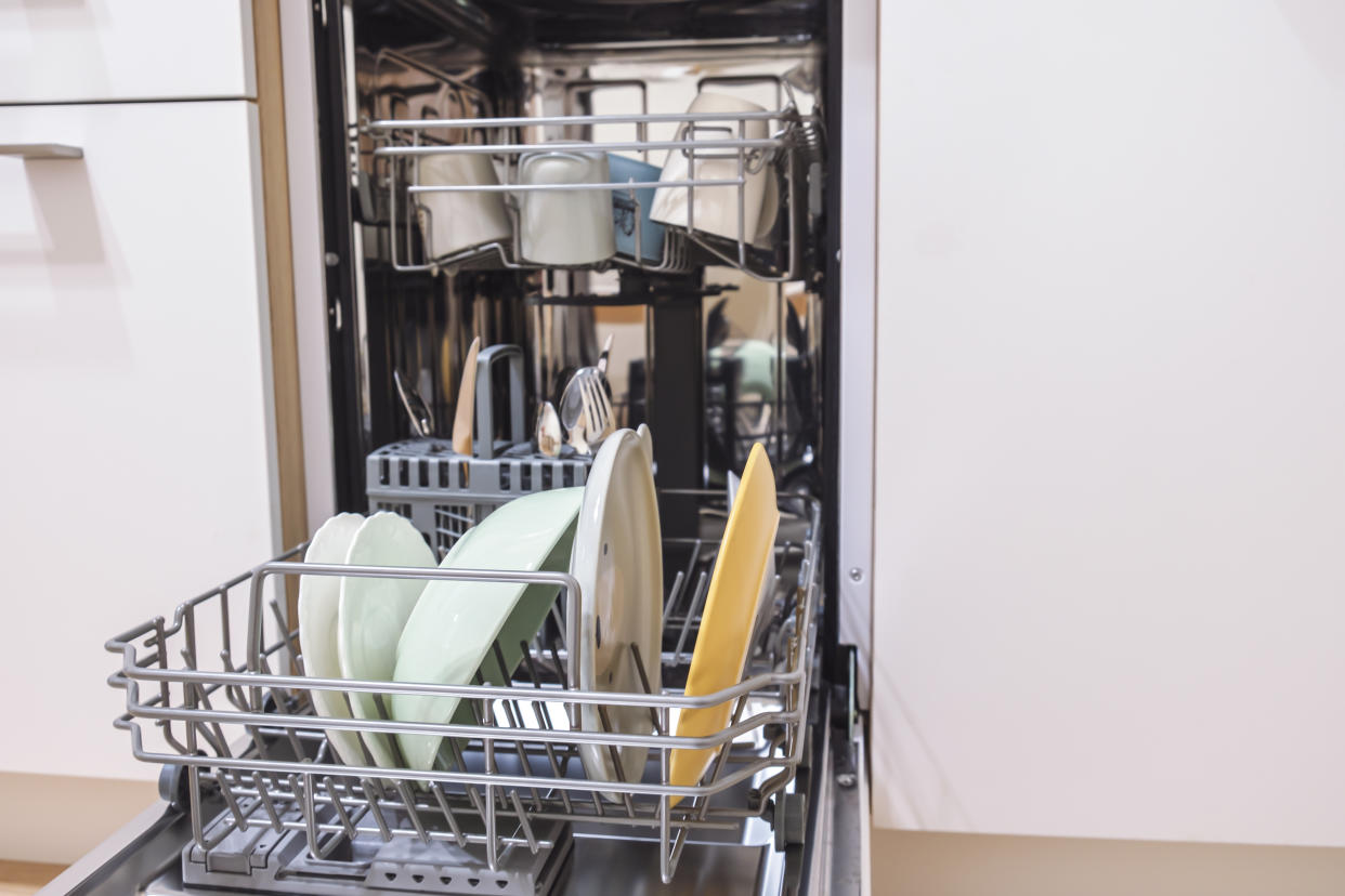 Open dishwasher with clean dishes. Close-up of the dishes placed in the dishwasher. Automatic dishwashing machine at home. Household chores. Selective focus