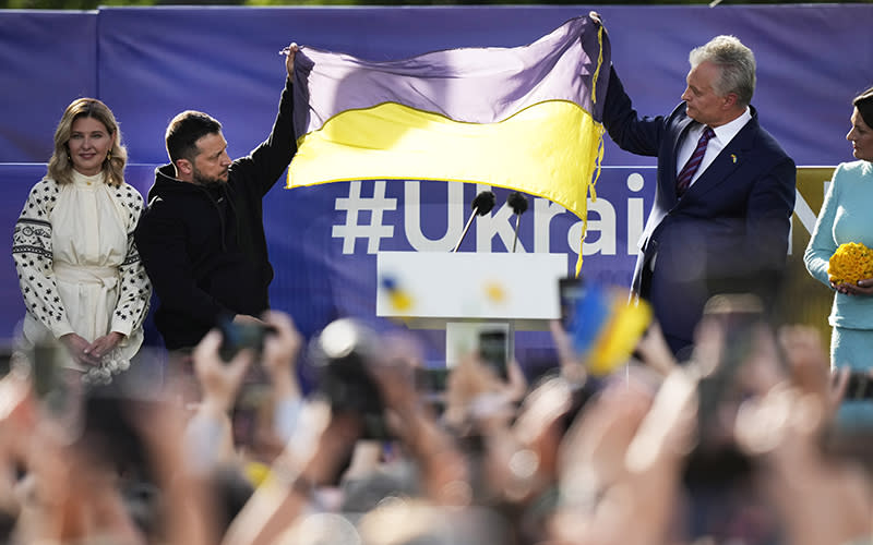 Ukraine's President Volodymyr Zelenskyy and Lithuania's President Gitanas Nauseda hold up a Ukrainian flag as they address the crowd during an event