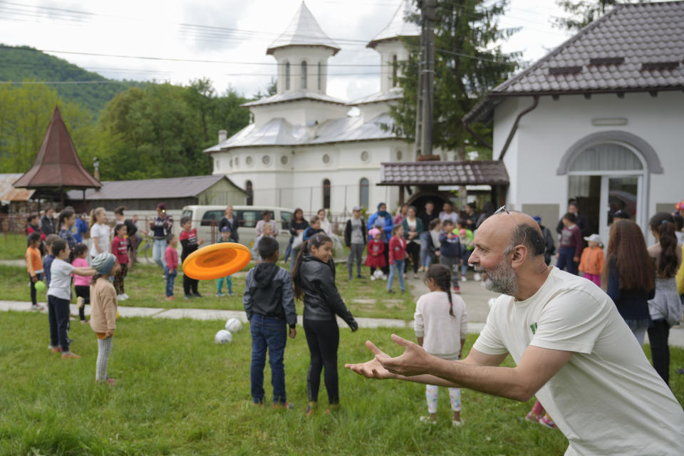 Valeriu Nicolae, the founder of the Casa Buna NGO, catches a frisbee thrown by a child during an eyesight examination performed by volunteer ophthalmologists, in Nucsoara, Romania, Saturday, May 29, 2021. (AP Photo/Vadim Ghirda)